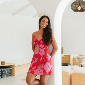 Woman wearing red sleeveless mini dress with large pink flowers print.