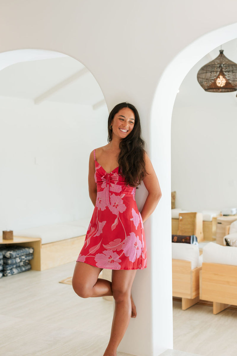 Woman wearing red sleeveless mini dress with large pink flowers print.