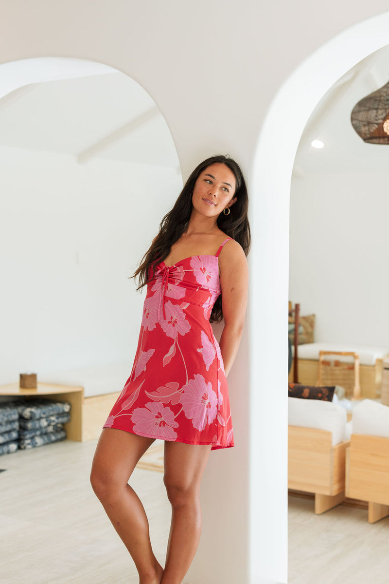 Woman wearing red sleeveless mini dress with large pink flowers print.