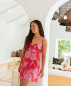 Woman wearing red sleeveless mini dress with large pink flowers print.