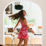Woman wearing red sleeveless mini dress with large pink flowers print.