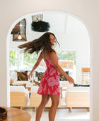 Woman wearing red sleeveless mini dress with large pink flowers print.