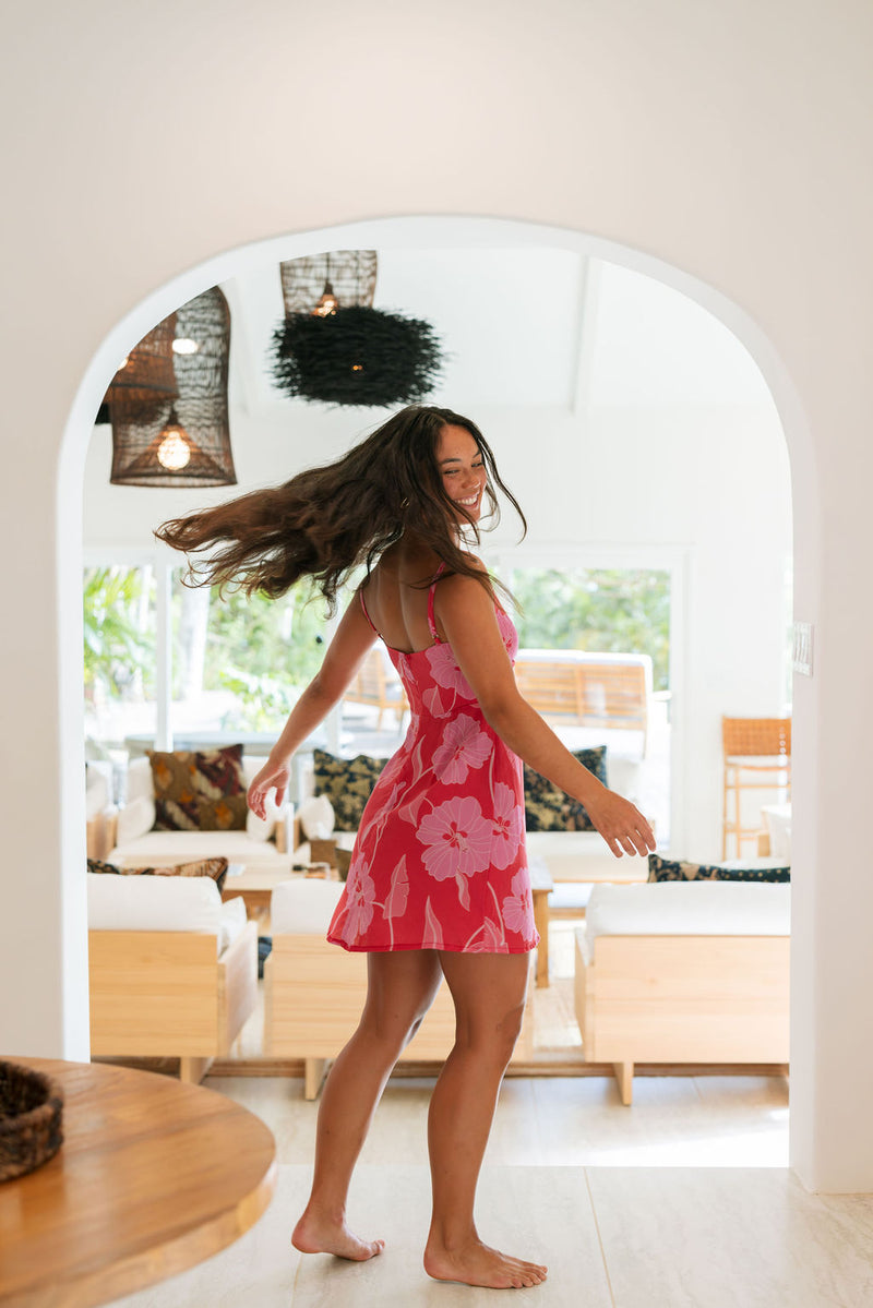 Woman wearing red sleeveless mini dress with large pink flowers print.