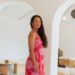 Woman wearing red sleeveless mini dress with large pink flowers print.