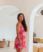 Woman wearing red sleeveless mini dress with large pink flowers print.