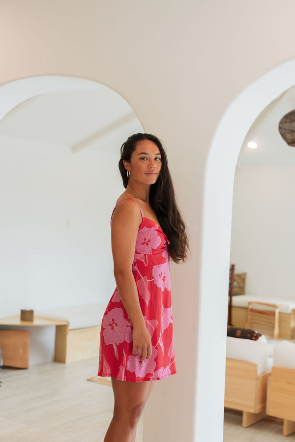 Woman wearing red sleeveless mini dress with large pink flowers print.