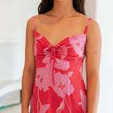 Woman wearing red sleeveless mini dress with large pink flowers print.