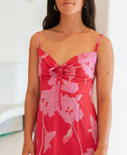 Woman wearing red sleeveless mini dress with large pink flowers print.