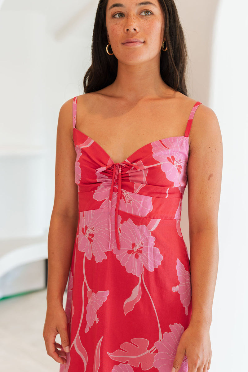 Woman wearing red sleeveless mini dress with large pink flowers print.