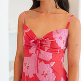 Woman wearing red sleeveless mini dress with large pink flowers print.