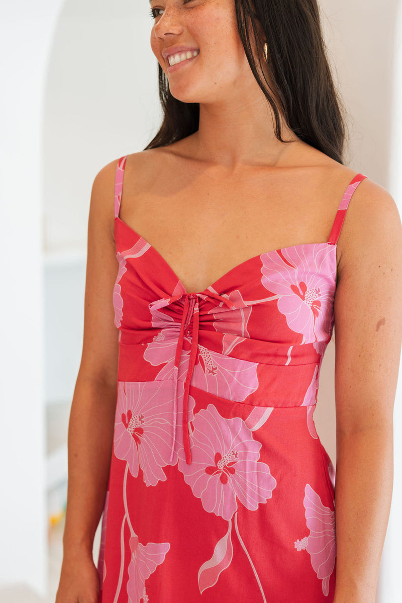 Woman wearing red sleeveless mini dress with large pink flowers print.