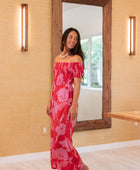 Woman wearing long red off shoulder jumpsuit with large pink floral print.