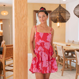 Woman wearing short red sleeveless dress with large pink floral print.