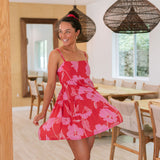 Woman wearing short red sleeveless dress with large pink floral print.