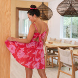 Woman wearing short red sleeveless dress with large pink floral print.