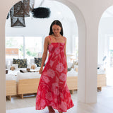 Woman wearing red sleeveless maxi dress with large pink floral print.