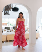 Woman wearing red sleeveless maxi dress with large pink floral print.