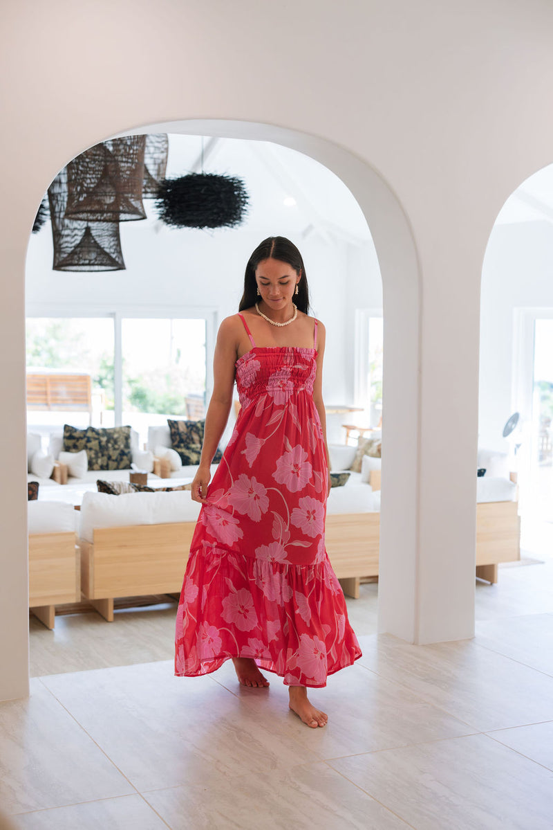 Woman wearing red sleeveless maxi dress with large pink floral print.