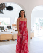 Woman wearing red sleeveless maxi dress with large pink floral print.