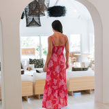 Woman wearing red sleeveless maxi dress with large pink floral print.