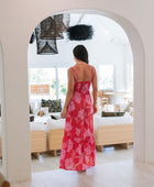 Woman wearing red sleeveless maxi dress with large pink floral print.