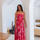 Woman wearing red sleeveless maxi dress with large pink floral print.