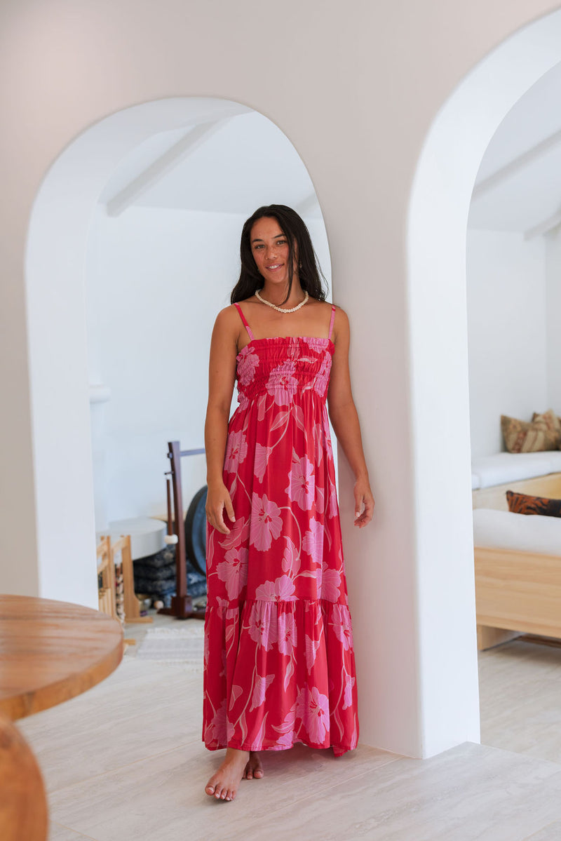 Woman wearing red sleeveless maxi dress with large pink floral print.