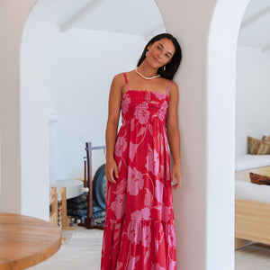 Woman wearing red sleeveless maxi dress with large pink floral print.