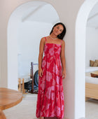 Woman wearing red sleeveless maxi dress with large pink floral print.