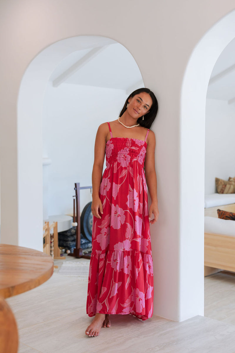 Woman wearing red sleeveless maxi dress with large pink floral print.