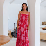 Woman wearing red sleeveless maxi dress with large pink floral print.