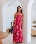 Woman wearing red sleeveless maxi dress with large pink floral print.