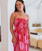 Woman wearing red sleeveless maxi dress with large pink floral print.