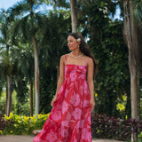 Woman wearing red sleeveless maxi dress with large pink floral print.