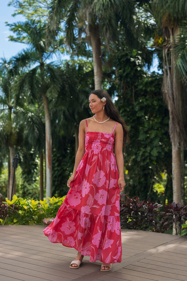 Woman wearing red sleeveless maxi dress with large pink floral print.