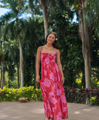 Woman wearing red sleeveless maxi dress with large pink floral print.