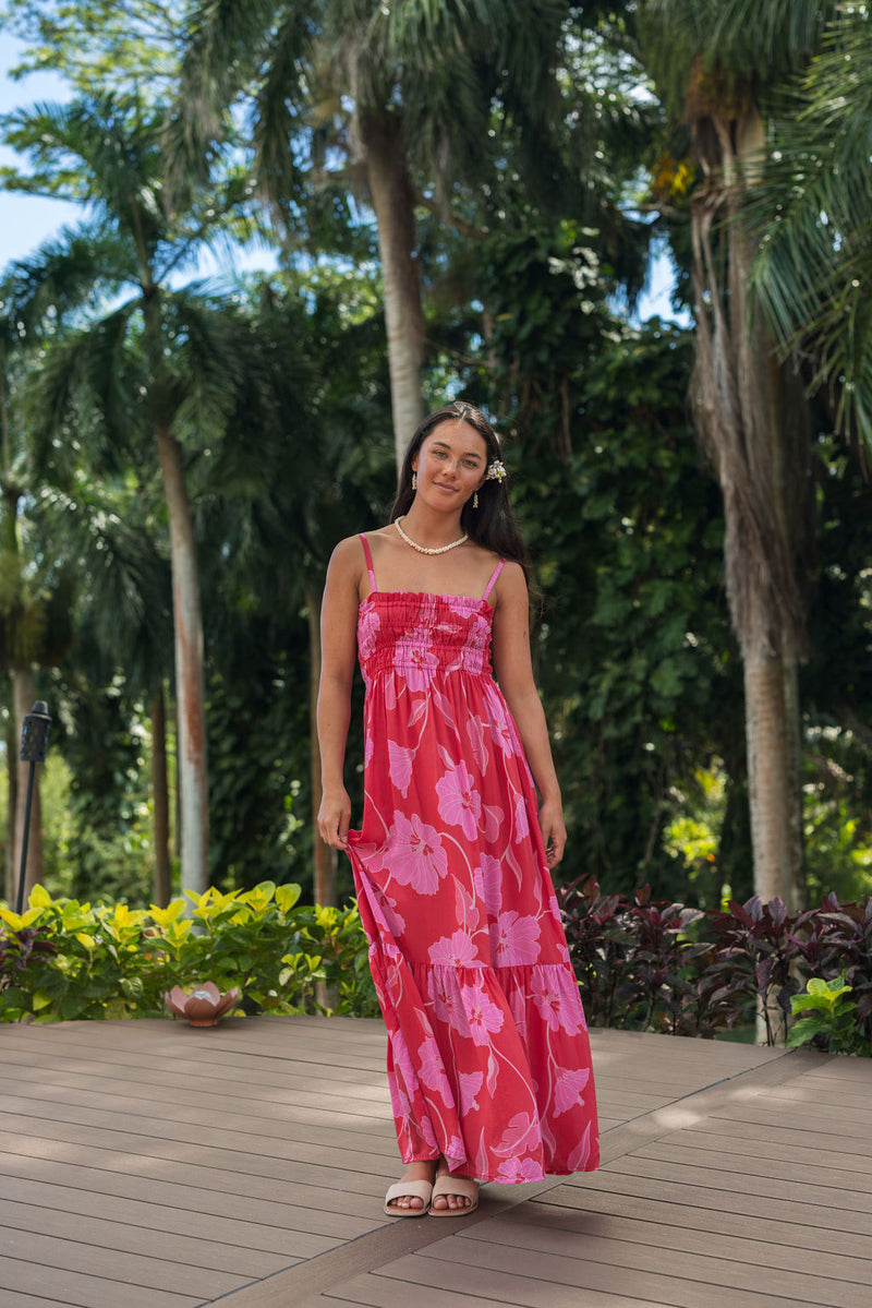 Woman wearing red sleeveless maxi dress with large pink floral print.