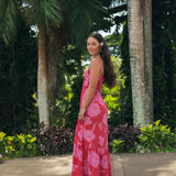 Woman wearing red sleeveless maxi dress with large pink floral print.