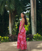 Woman wearing red sleeveless maxi dress with large pink floral print.