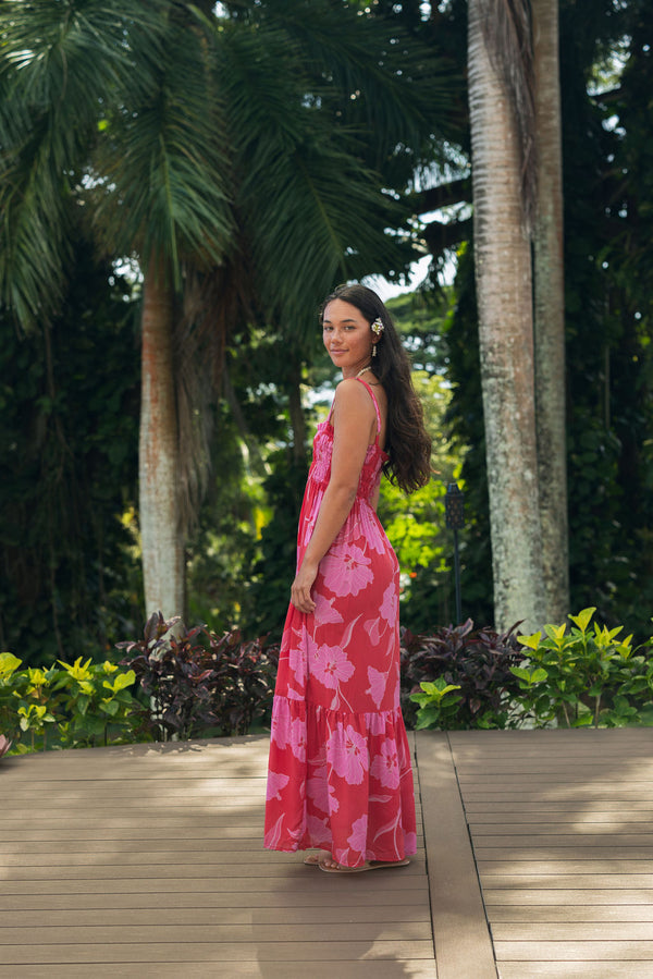 Woman wearing red sleeveless maxi dress with large pink floral print.