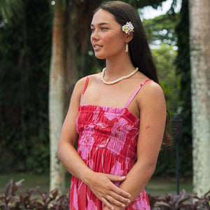 Woman wearing red sleeveless maxi dress with large pink floral print.