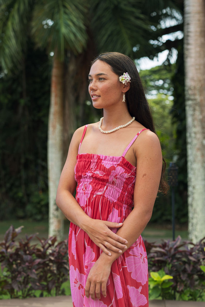 Woman wearing red sleeveless maxi dress with large pink floral print.