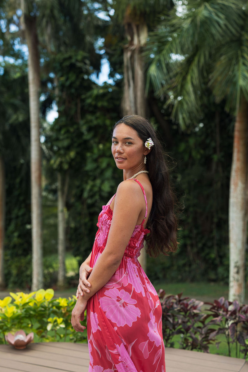 Woman wearing red sleeveless maxi dress with large pink floral print.