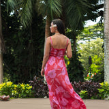 Woman wearing red sleeveless maxi dress with large pink floral print.