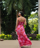 Woman wearing red sleeveless maxi dress with large pink floral print.