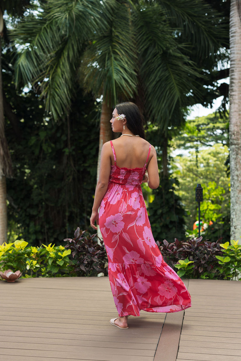 Woman wearing red sleeveless maxi dress with large pink floral print.