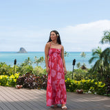 Woman wearing red sleeveless maxi dress with large pink floral print.