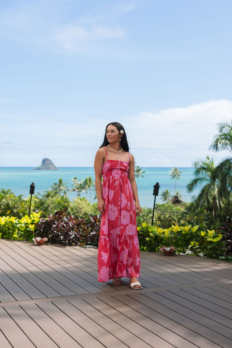 Woman wearing red sleeveless maxi dress with large pink floral print.