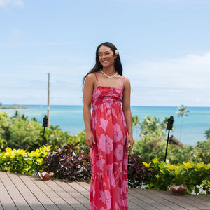 Woman wearing red sleeveless maxi dress with large pink floral print.