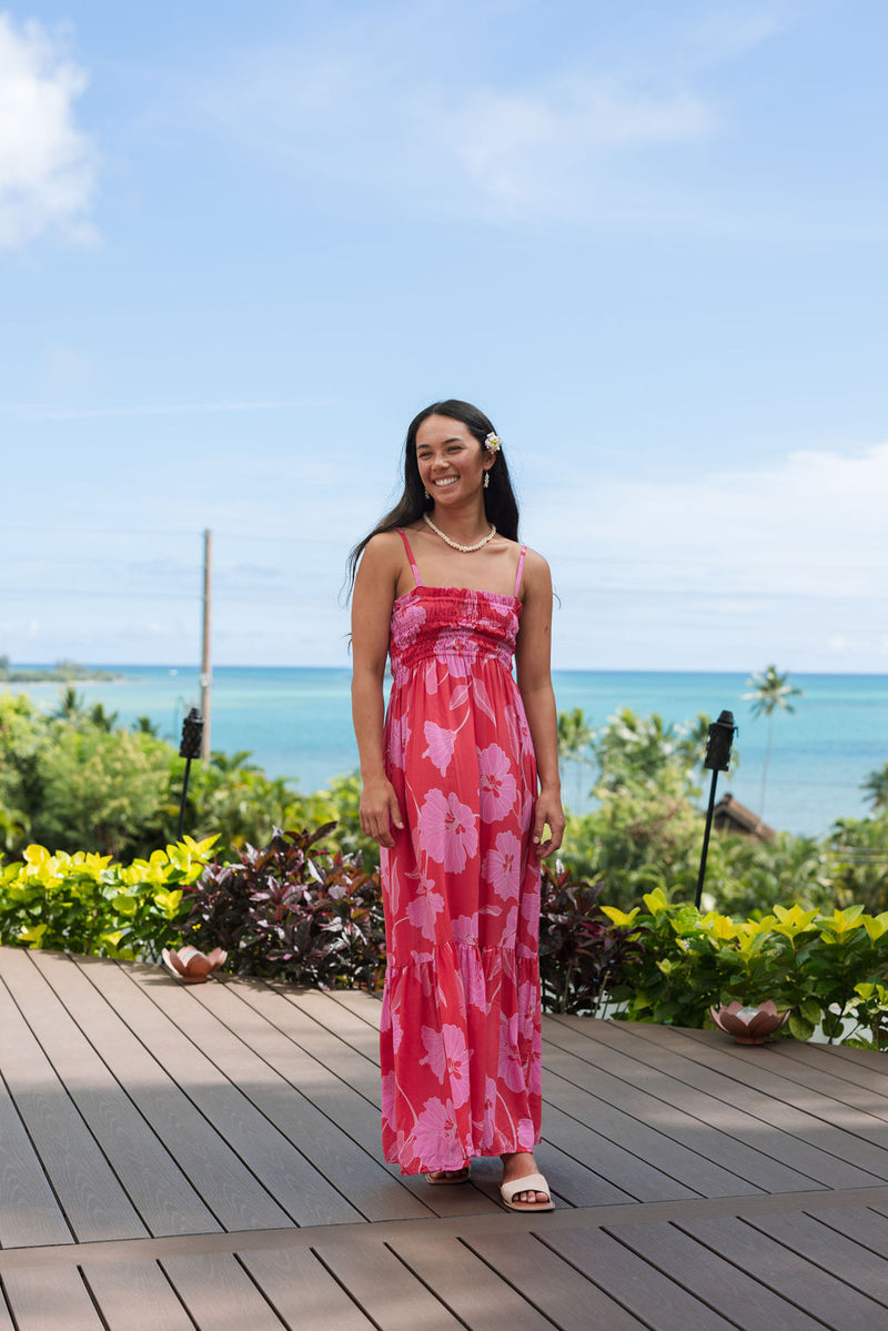 Woman wearing red sleeveless maxi dress with large pink floral print.